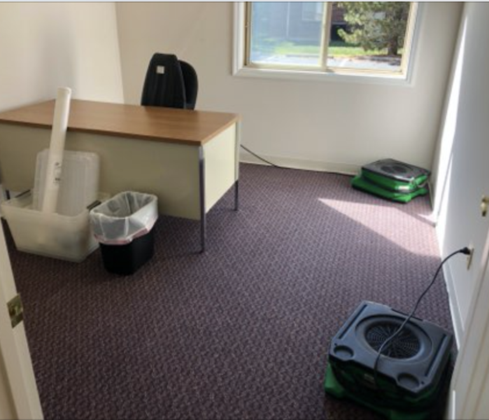 Office space with a desk and green drying equipment.